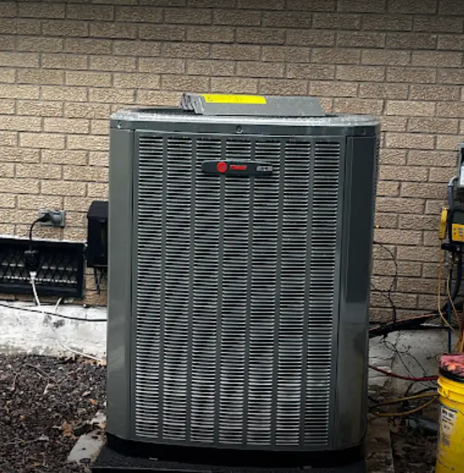 An outdoor Trane condenser installed against brick siding at a Belleville area home